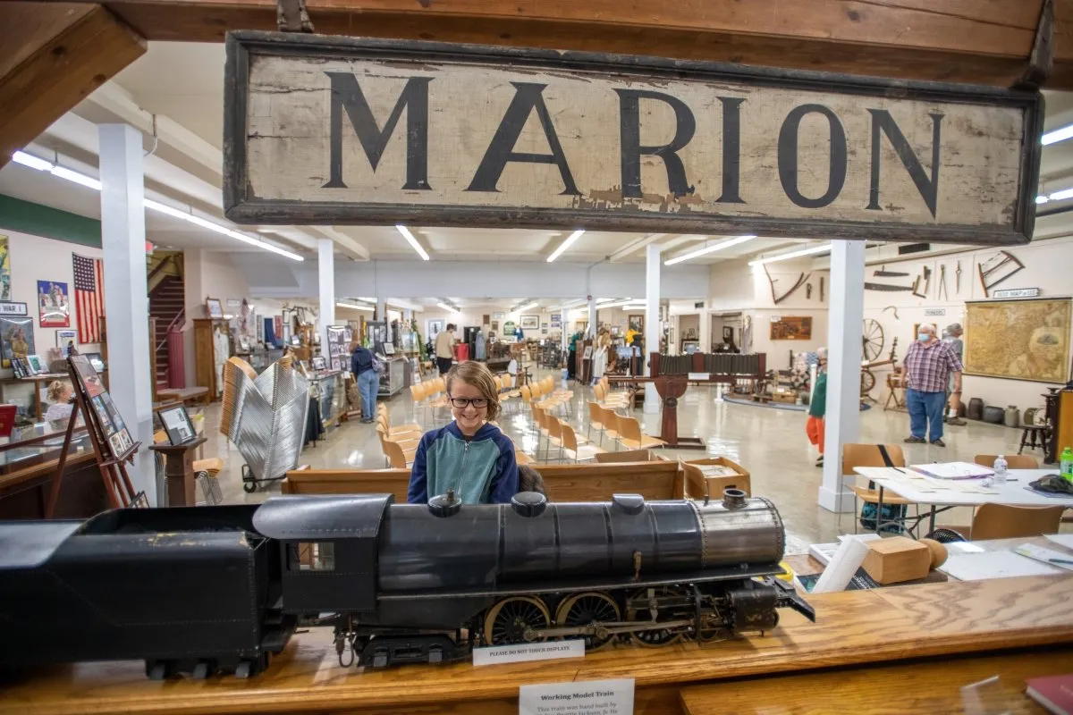 Visitors exploring the Smyth County Museum, with a model locomotive beneath the historic Marion sign